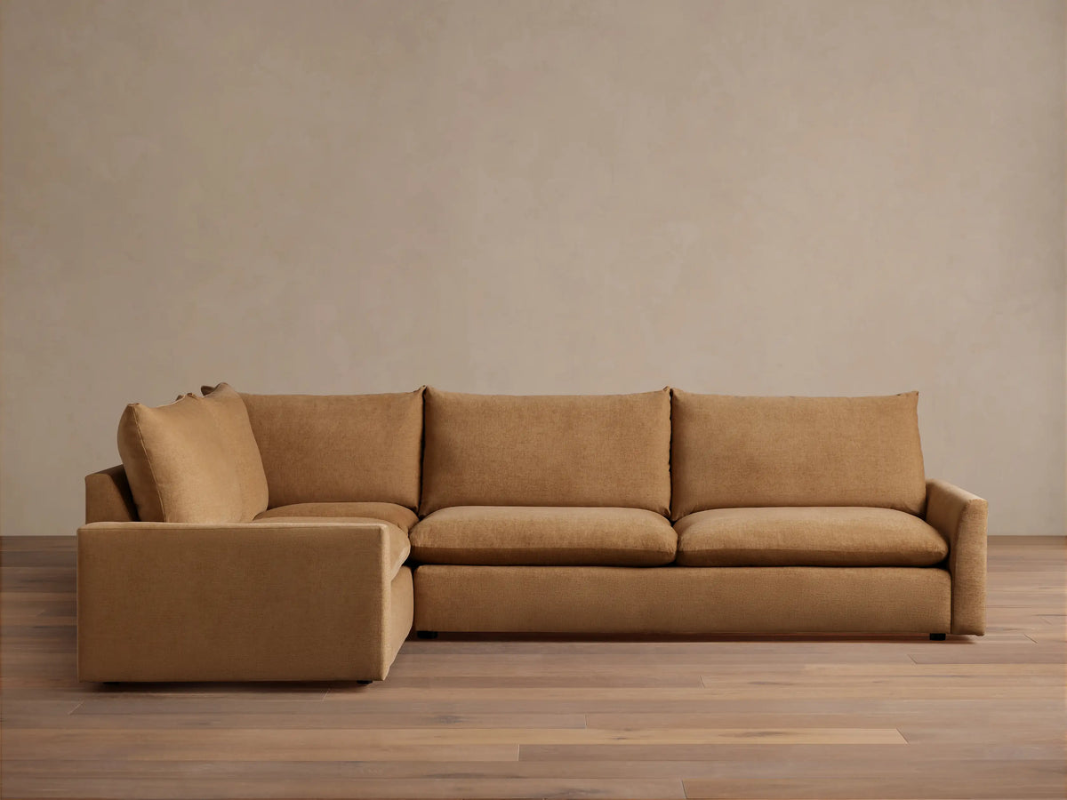 Calistoga Two-Piece Sectional in a light brown fabric. L-shaped design with plush cushions, set on a wooden floor against a neutral wall.