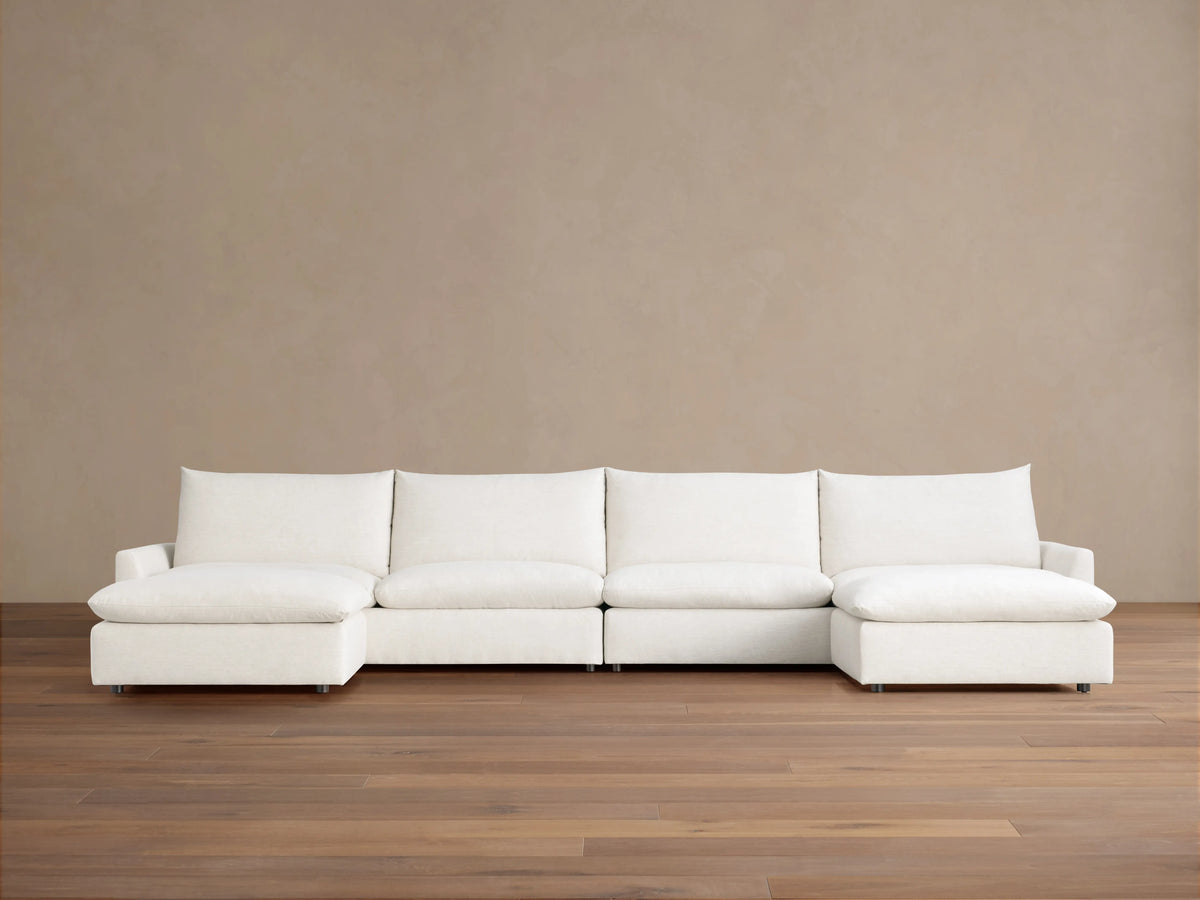 Calistoga Four-Piece Sectional in off-white, with left and right chaises, against a neutral brown wall and wood floor.