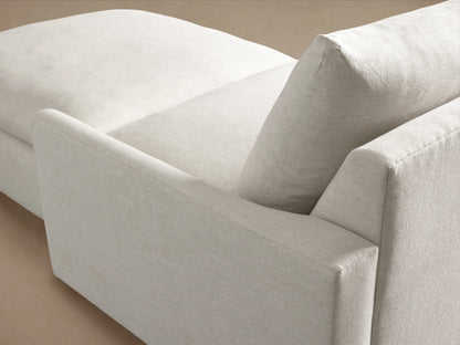 Close-up of Calistoga Sectional's textured light beige performance fabric, showing a soft armrest, back cushion, and chaise.