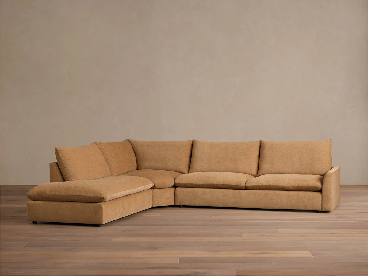 Front view of a tan Calistoga Three-Piece Bumper Sectional, showcasing its plush, relaxed design with a deep chaise lounge.
