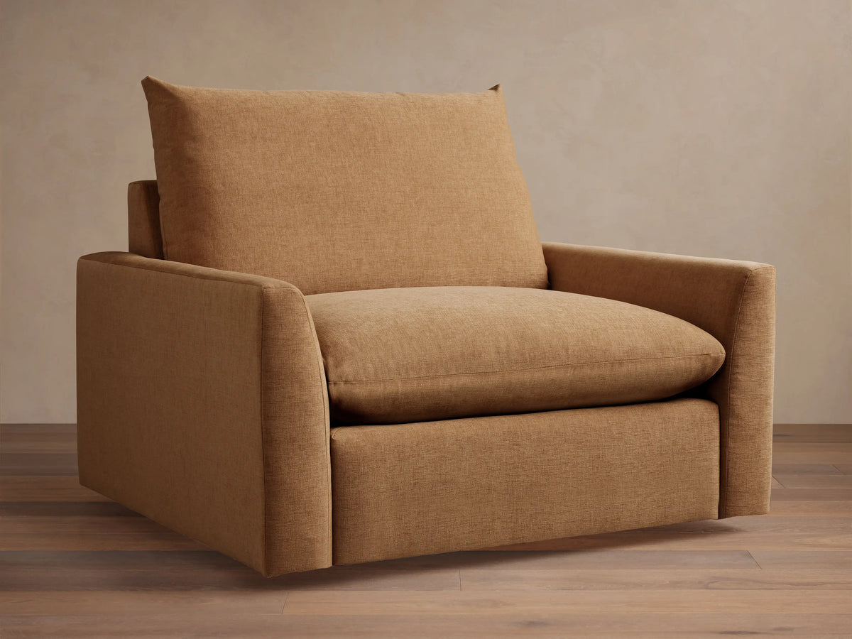 Brown Calistoga Chair with plush seat and back cushion, featuring soft fabric, minimalist design and wide armrests on wood floor.