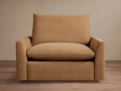 Brown Calistoga Chair with plush seat and back cushion, featuring soft fabric, minimalist design and wide armrests on wood floor.