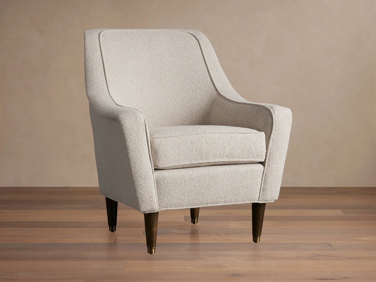 Ecru Archie Chair in textured performance fabric, featuring rounded arms, a high back, and dark tapered wood legs with brass caps.