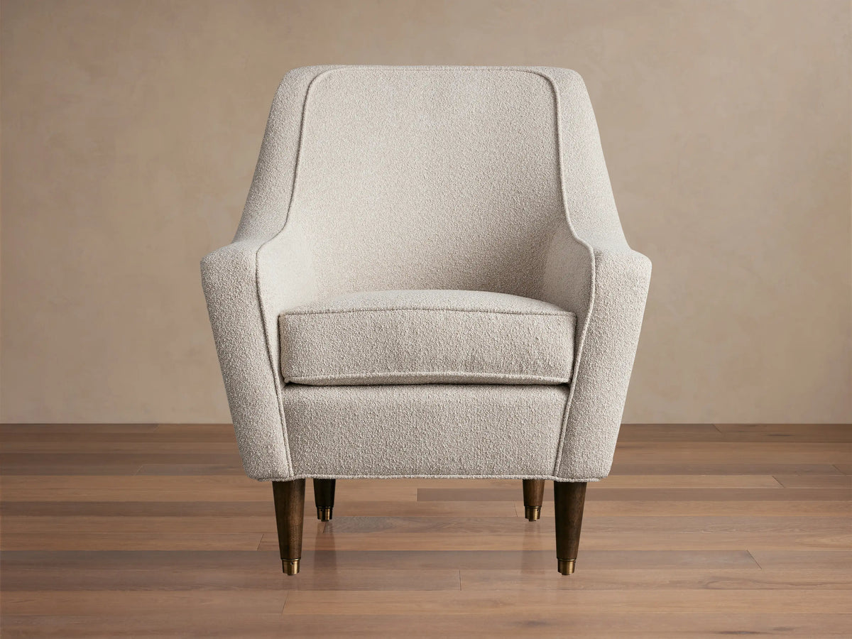 Ecru Archie Chair in textured performance fabric, featuring rounded arms, a high back, and dark tapered wood legs with brass caps.