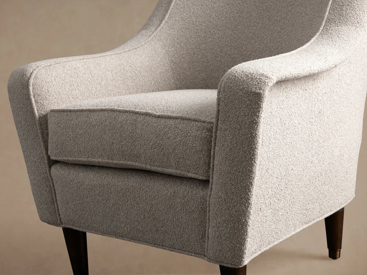 Archie Chair in light ecru textured performance fabric, with tapered arms & dark wood legs with brass caps, on hardwood floor.