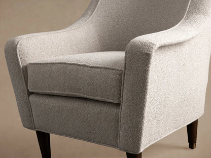 Archie Chair in light ecru textured performance fabric, with tapered arms & dark wood legs with brass caps, on hardwood floor.