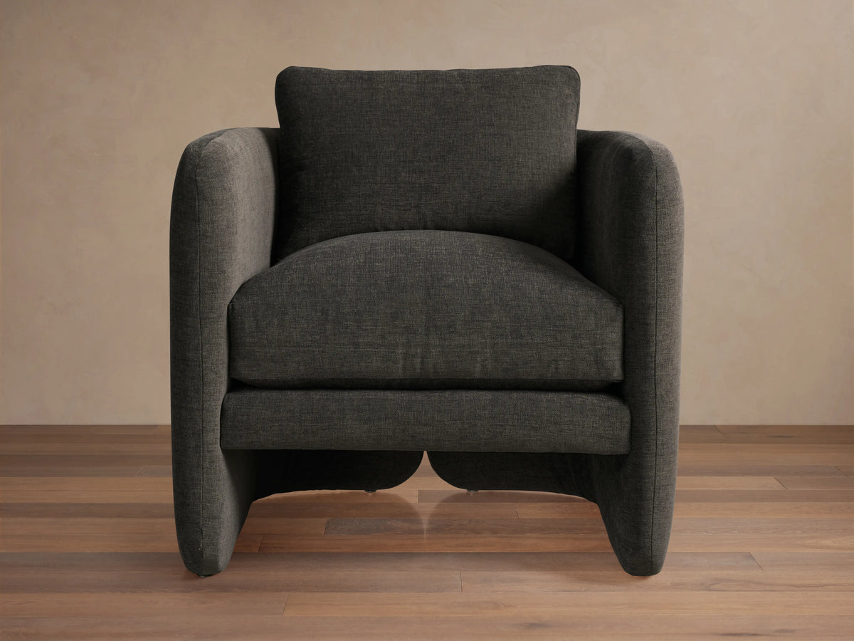 Front view of the Dalia Chair, a modern dark charcoal gray upholstered accent chair with soft lines on wood floor.