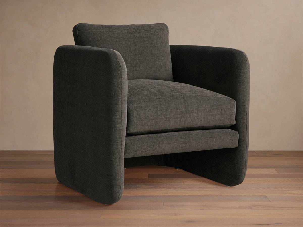 Front view of the Dalia Chair, a modern dark charcoal gray upholstered accent chair with soft lines on wood floor.