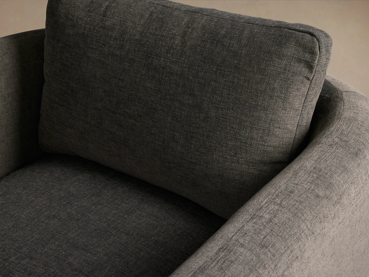 Modern Dalia Chair, dark grey textured fabric, boxy shape with wide upholstered arms, on a wooden floor.