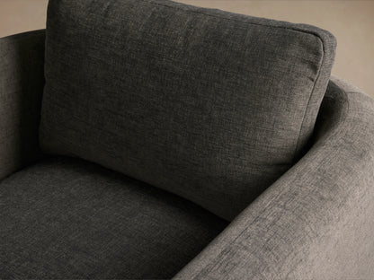 Modern Dalia Chair, dark grey textured fabric, boxy shape with wide upholstered arms, on a wooden floor.