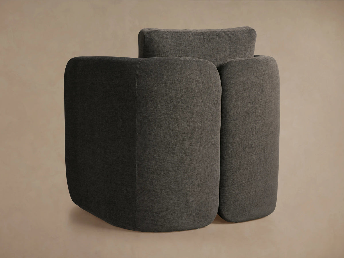 Close-up of a Dalia Chair in dark gray textured upholstery, showing the backrest cushion and curved arm.