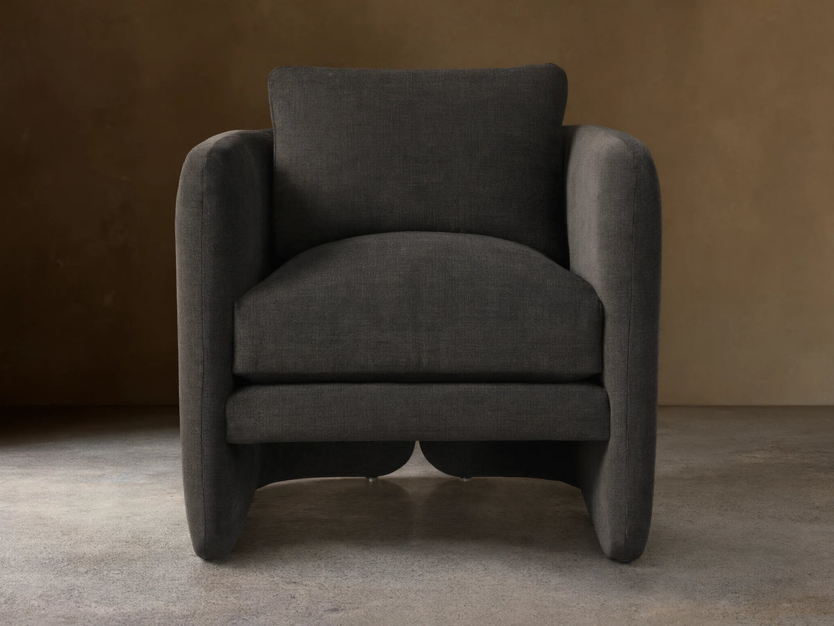 Front view of the Dalia Chair, a modern dark charcoal gray upholstered accent chair with soft lines on wood floor.
