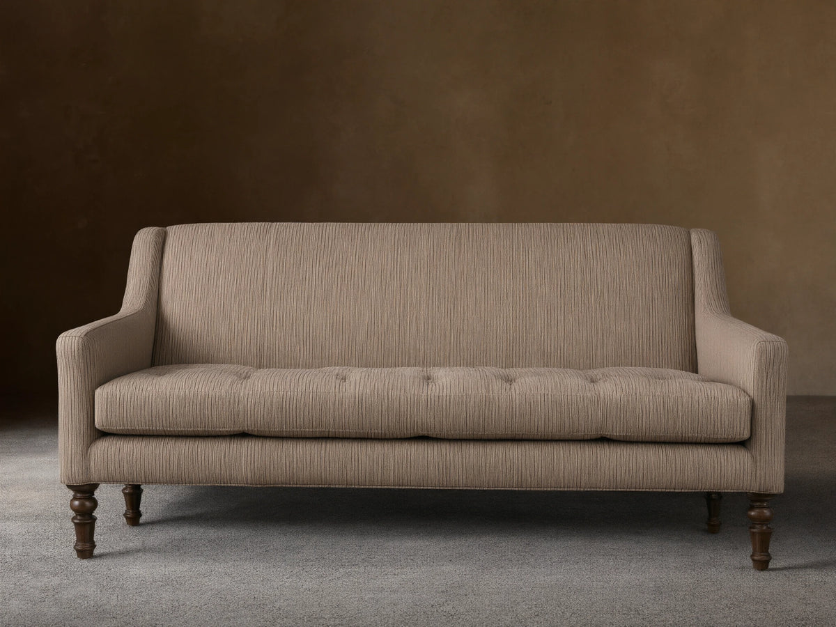 Fenwick Settee: Light beige settee with thin dark vertical stripes, tufted seat, sloped arms, dark turned wood legs, and nailhead trim.