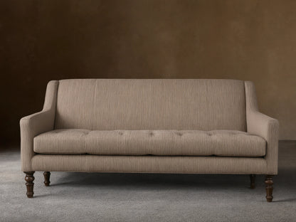 Fenwick Settee: Light beige settee with thin dark vertical stripes, tufted seat, sloped arms, dark turned wood legs, and nailhead trim.