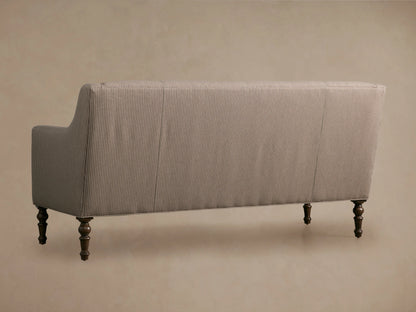 Taupe Fenwick Settee with subtle vertical pinstripes, elegant rolled arms, and dark turned wooden legs on a wood floor.