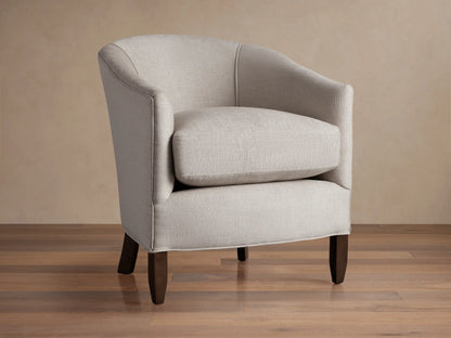 Giles Chair: Light neutral fabric armchair, curved back, separate seat cushion, dark wood legs. Angled slightly right on wood floor.