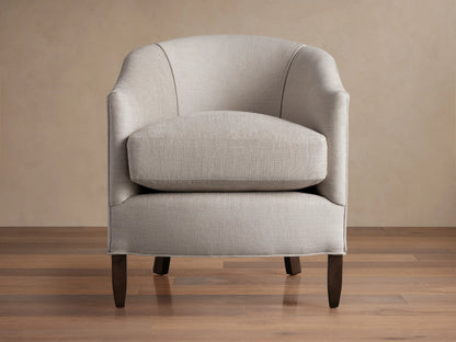 Giles Chair: Light neutral fabric armchair, curved back, separate seat cushion, dark wood legs. Angled slightly right on wood floor.