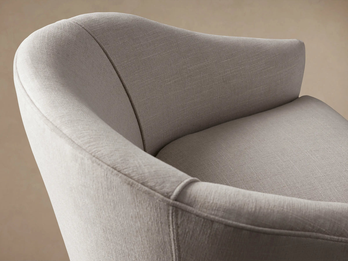 Giles Chair: Light beige fabric chair with a curved back, separate seat cushion, and dark tapered wooden legs, on a wood floor.