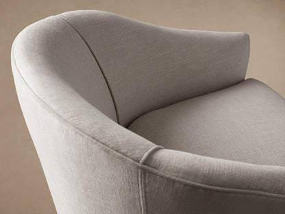 Giles Chair: Light beige fabric chair with a curved back, separate seat cushion, and dark tapered wooden legs, on a wood floor.