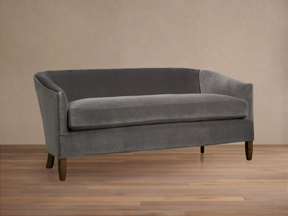 Giles Settee: Dark grey velvety loveseat with curved arms, single seat cushion, and dark wooden legs on a wood floor.