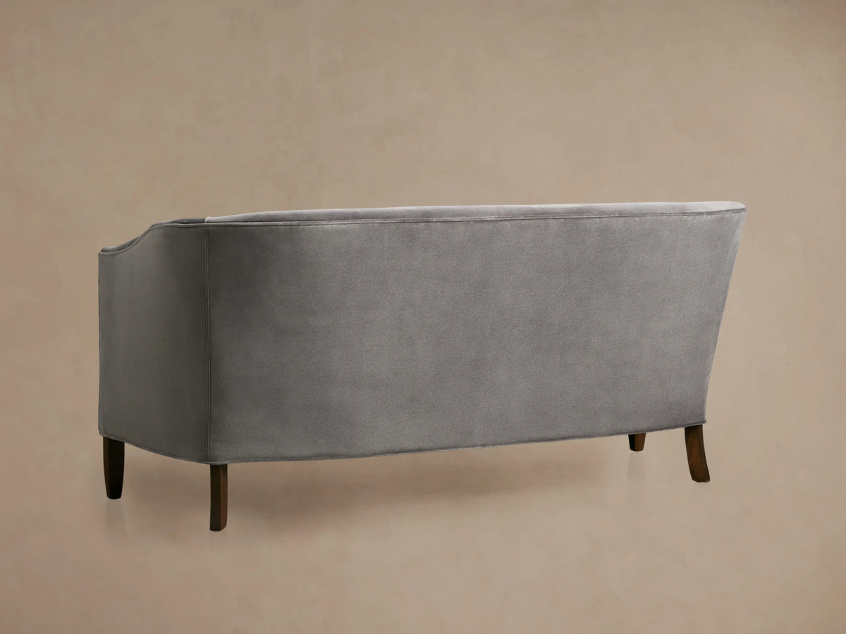 Close-up of Giles Settee in soft grey velvet upholstery, showing a plush, curved section with seam detail.