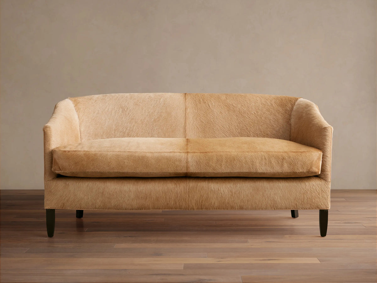 Front view of a light tan Giles Hair on Hide Settee with curved back, two seat cushions, and dark tapered legs.