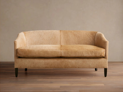 Front view of a light tan Giles Hair on Hide Settee with curved back, two seat cushions, and dark tapered legs.