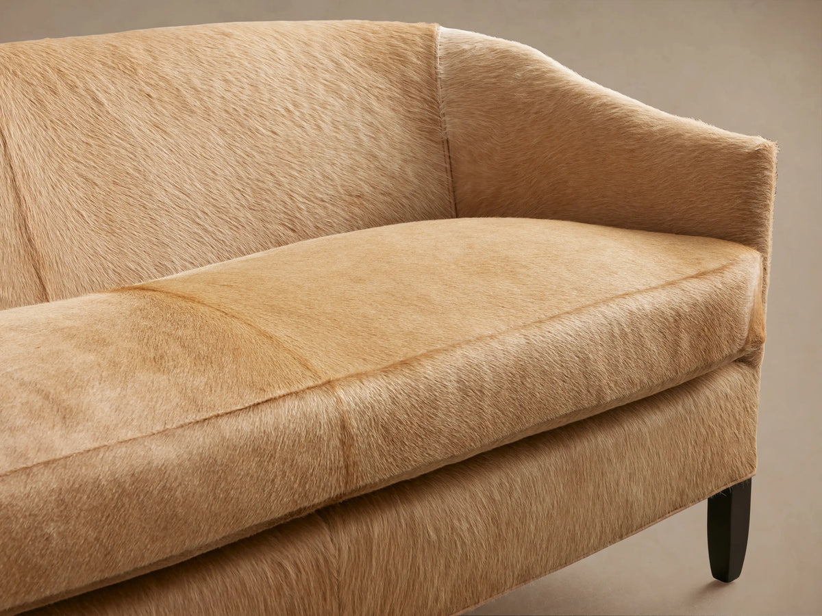 Front view of the light brown Giles Hair on Hide Settee with curved arms and dark legs.