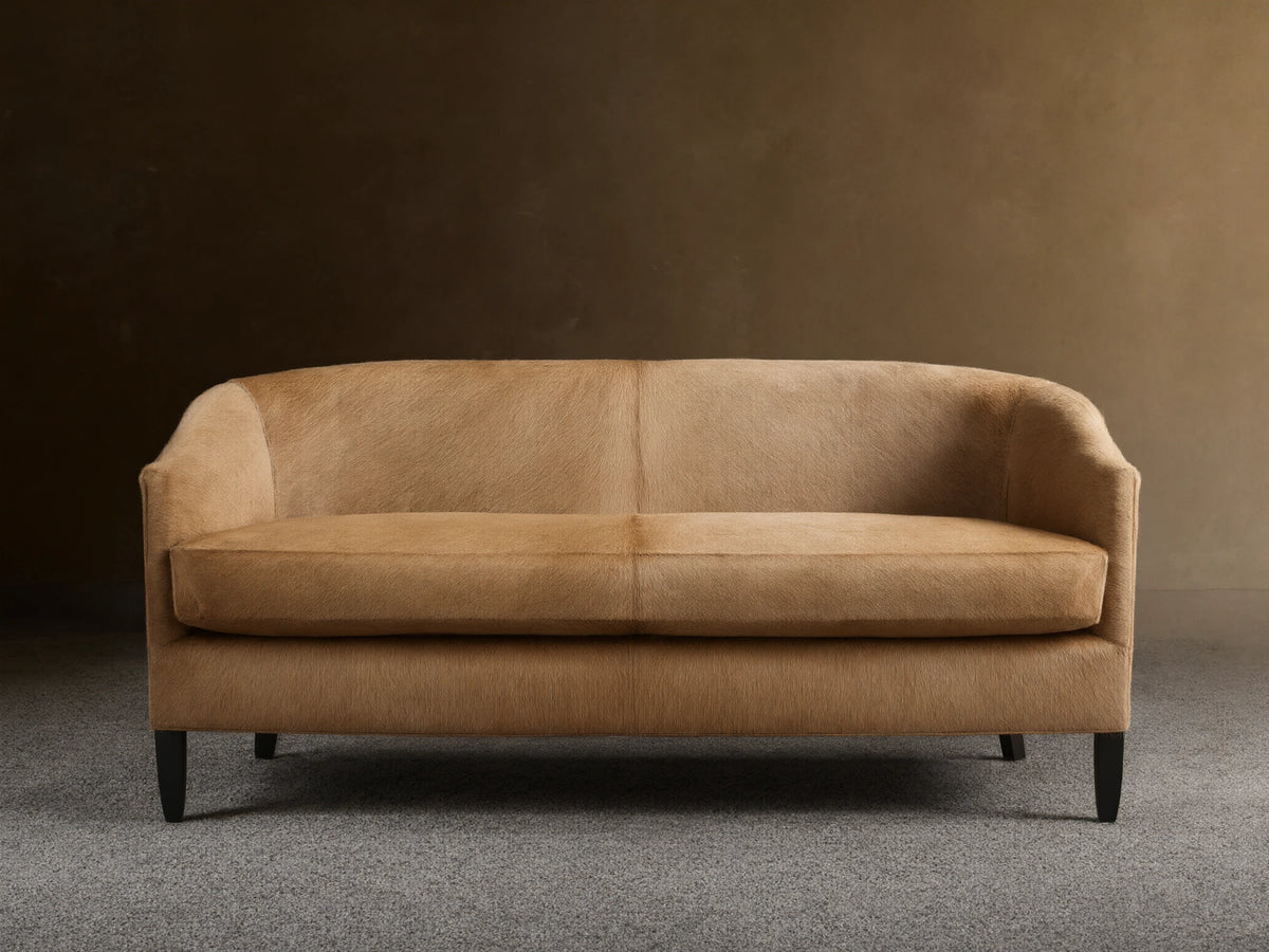 Front view of a light tan Giles Hair on Hide Settee with curved back, two seat cushions, and dark tapered legs.