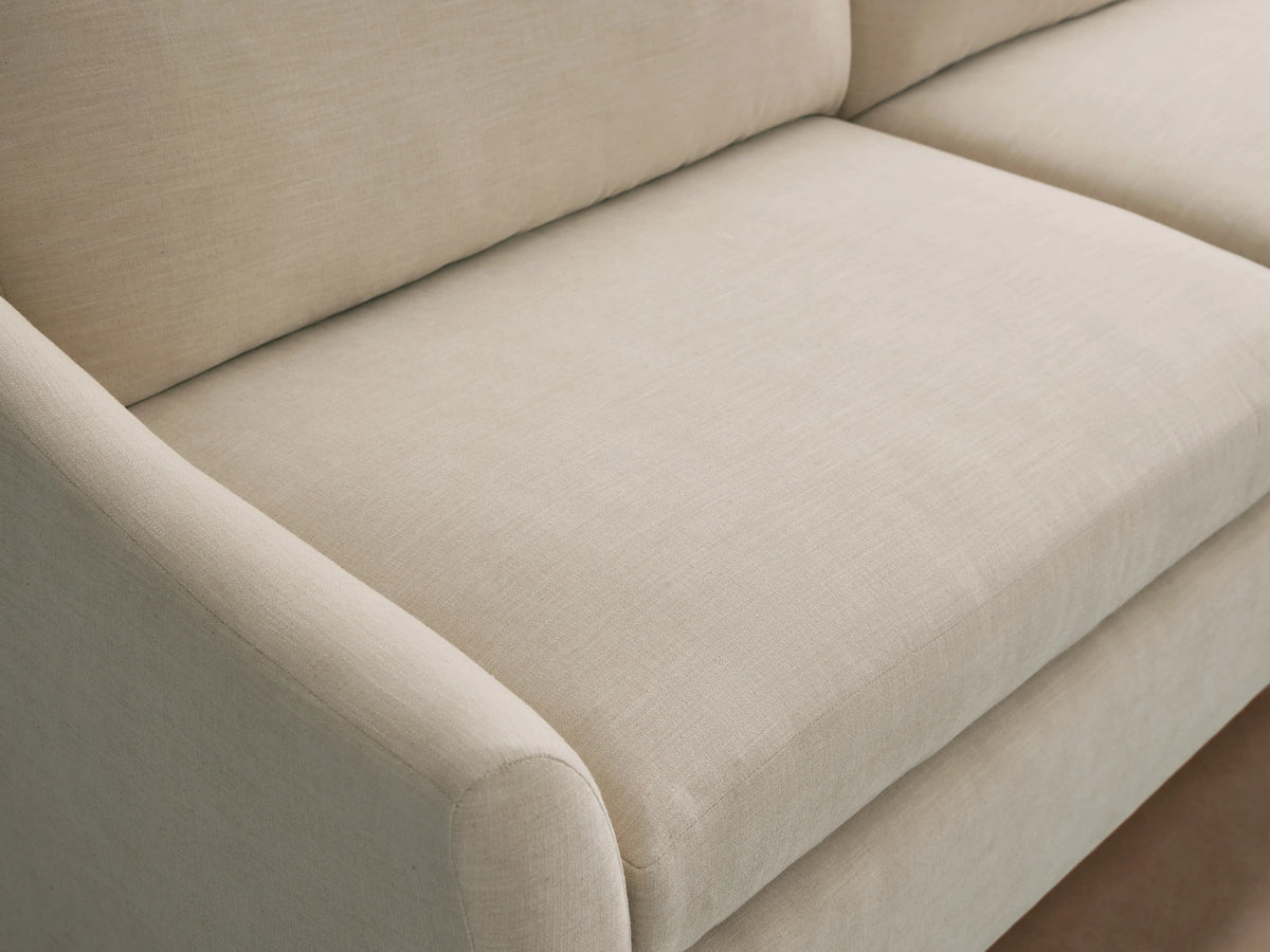 Light beige Helena Sofa with textured fabric, showing a rounded armrest, plush seat, and back cushions from an angled view.