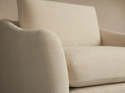 Helena Swivel Chair in a light beige fabric with a plush seat and back cushion, featuring curved armrests on a wooden floor.