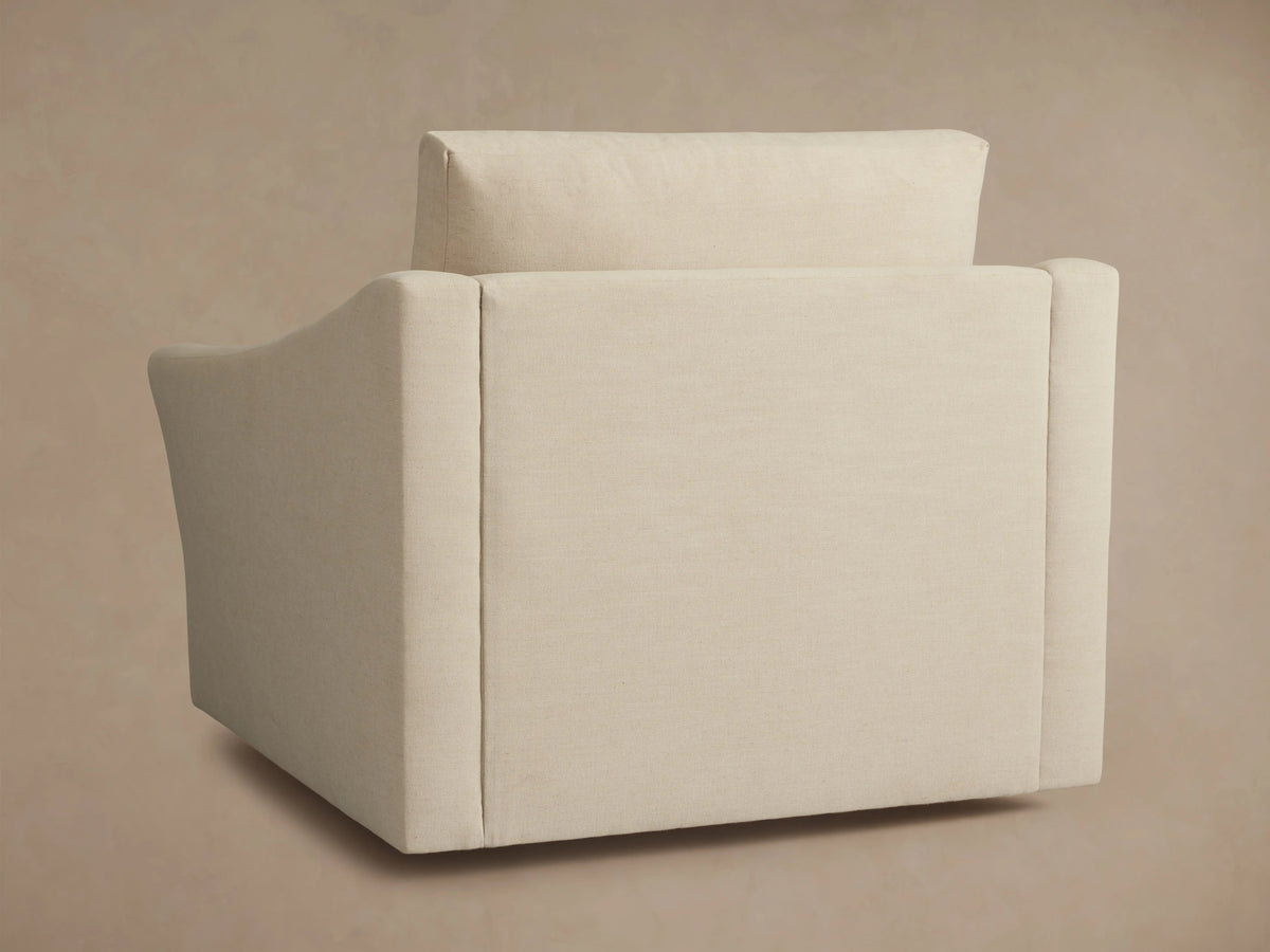 Alt text: Side view of the Helena Swivel Chair in cream-colored fabric, displaying its smooth, curved armrest and plush backrest.