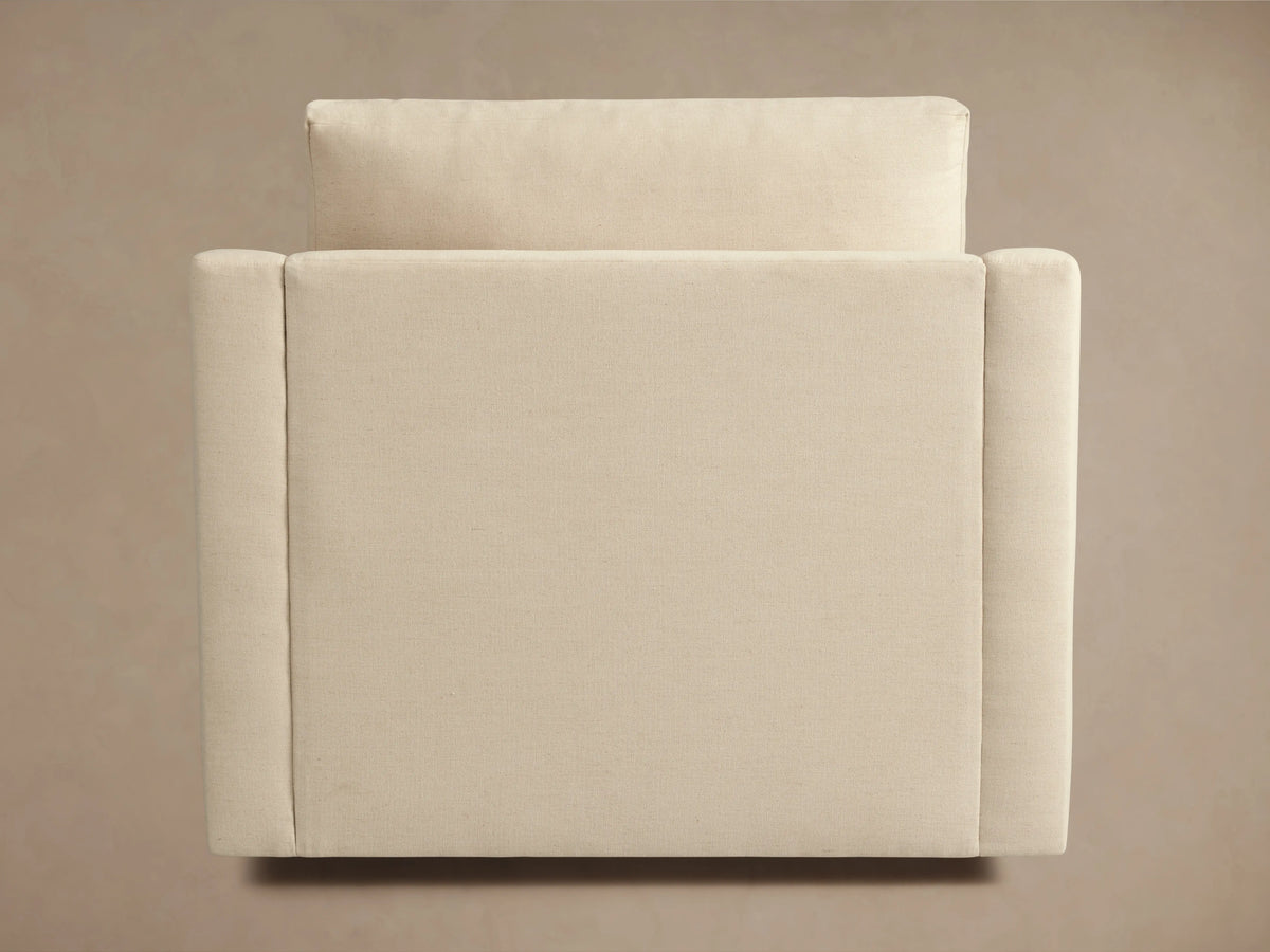 Helena Swivel Chair in beige fabric, viewed from the back showing its soft cushion and sleek, curved armrests on a neutral background.