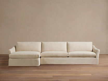Helena Slipcovered Two Piece Chaise Sectional in light cream fabric, left-facing chaise, skirted base, on wood floor.