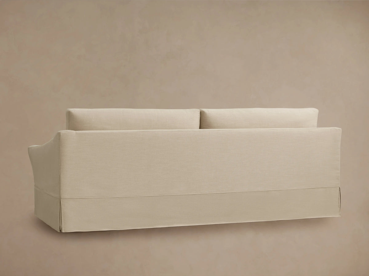 Helena Slipcovered Sofa in beige fabric, viewed from the back. Features a clean, simple design with two cushions and a full-length slipcover.