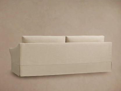 Helena Slipcovered Sofa in beige fabric, viewed from the back. Features a clean, simple design with two cushions and a full-length slipcover.