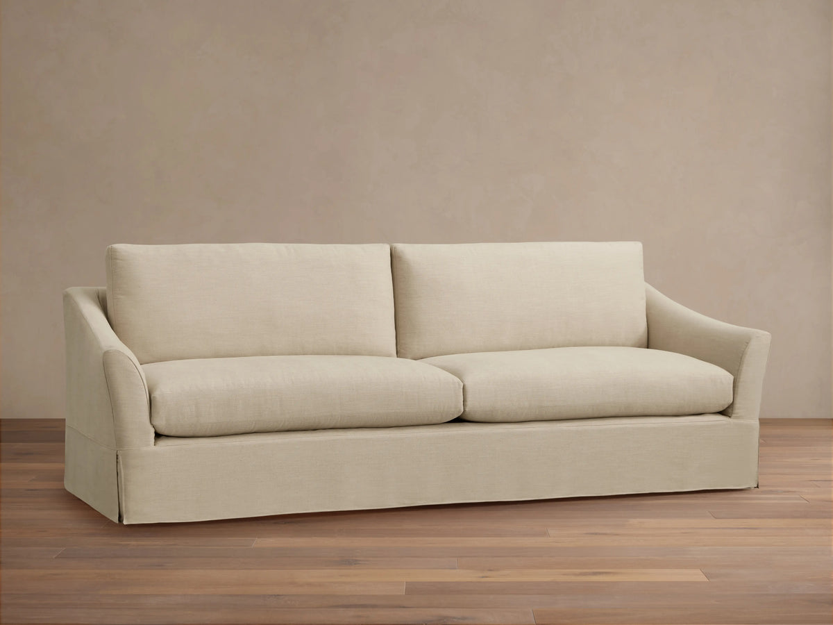 Beige Helena Slipcovered Sofa close-up showing the smooth, soft fabric texture, plush cushion, and rounded armrest design.