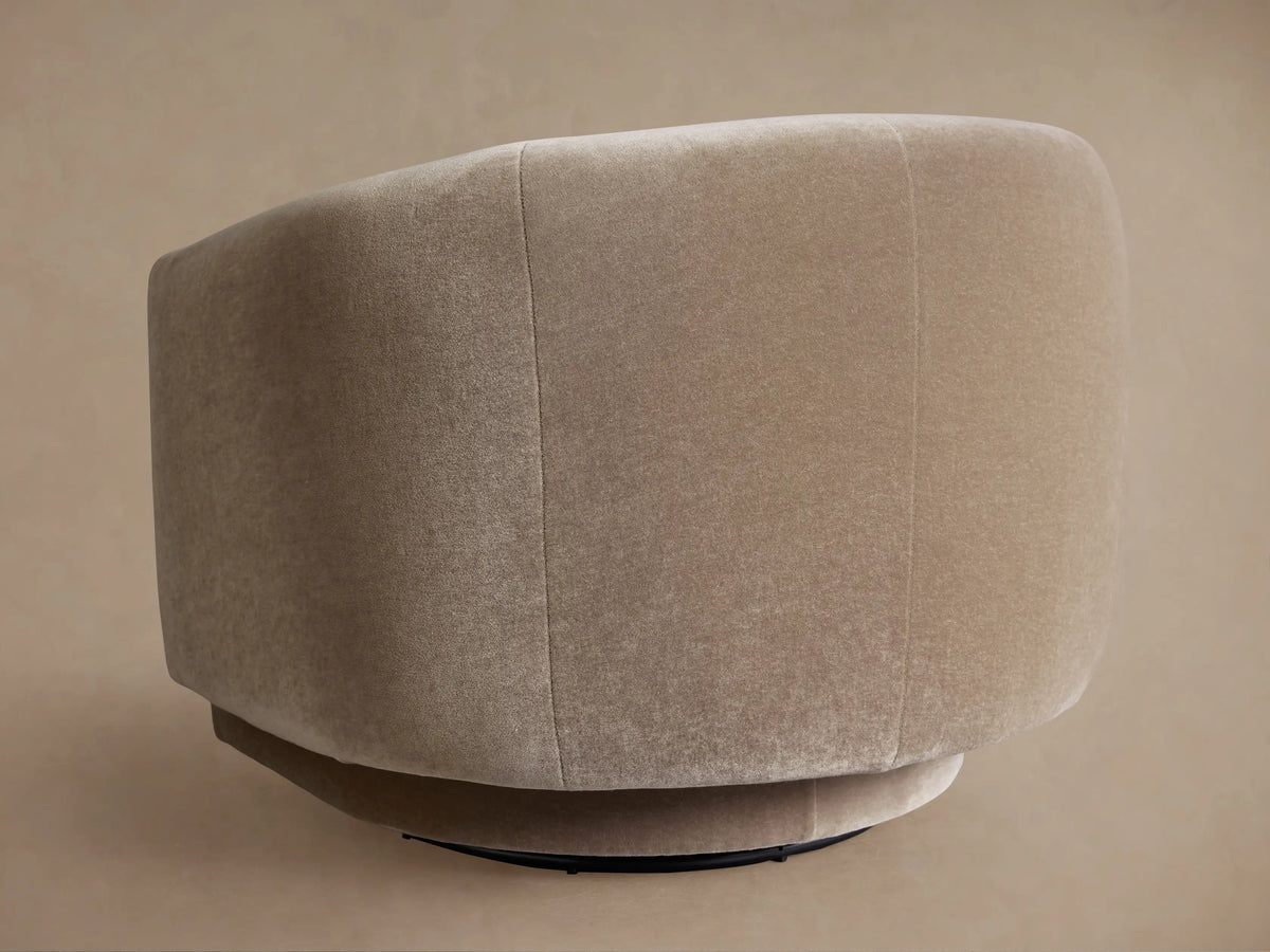Close-up of a Hamlin Swivel Chair, upholstered in soft, warm beige fabric, showcasing its curved barrel back and integrated arms.