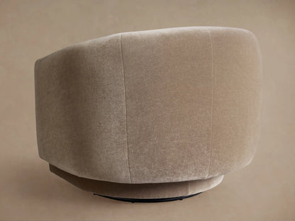 Close-up of a Hamlin Swivel Chair, upholstered in soft, warm beige fabric, showcasing its curved barrel back and integrated arms.