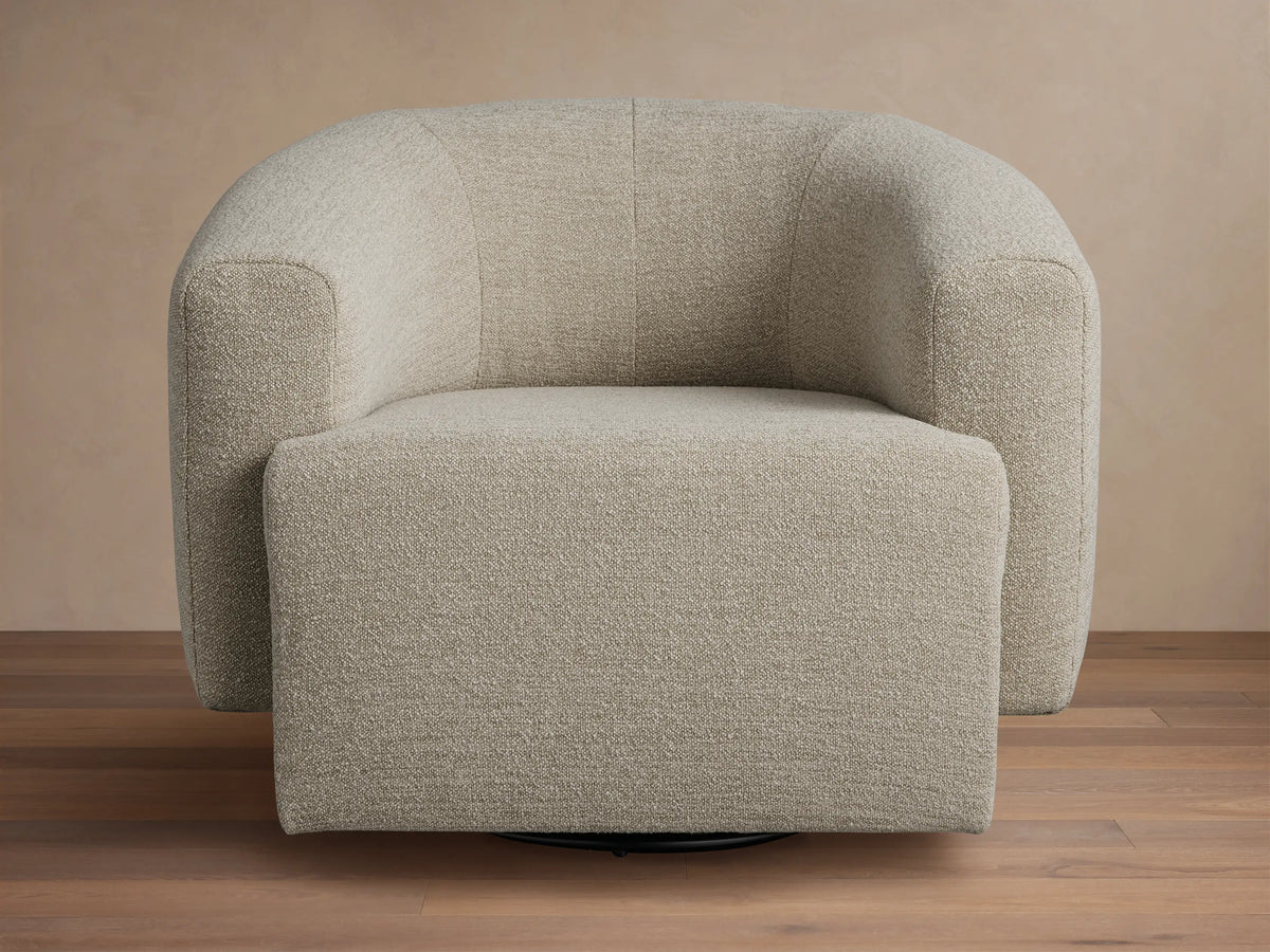 Two Mustard Hamlin Swivel Chairs with rounded backs, positioned in a living room with a patterned sofa and coffee table.