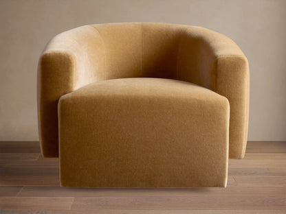 Two caramel Hamlin Swivel Chairs™ with curved backs, in a sunlit living room with a blue floral sectional.