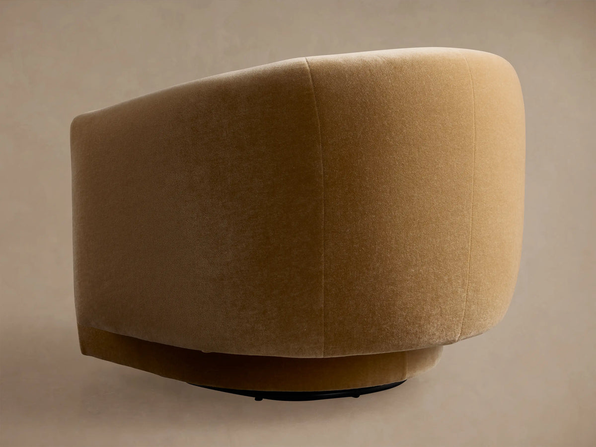 Close-up of the curved back and arm of a golden-brown velvet Hamlin Swivel Chair, showing soft texture and shadows.
