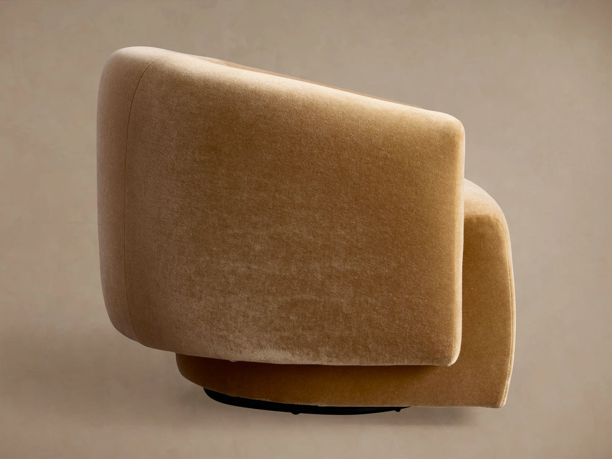 Hamlin Swivel Chair, upholstered in camel velvet, side view with a smoothly rounded back and seat, on a neutral background.