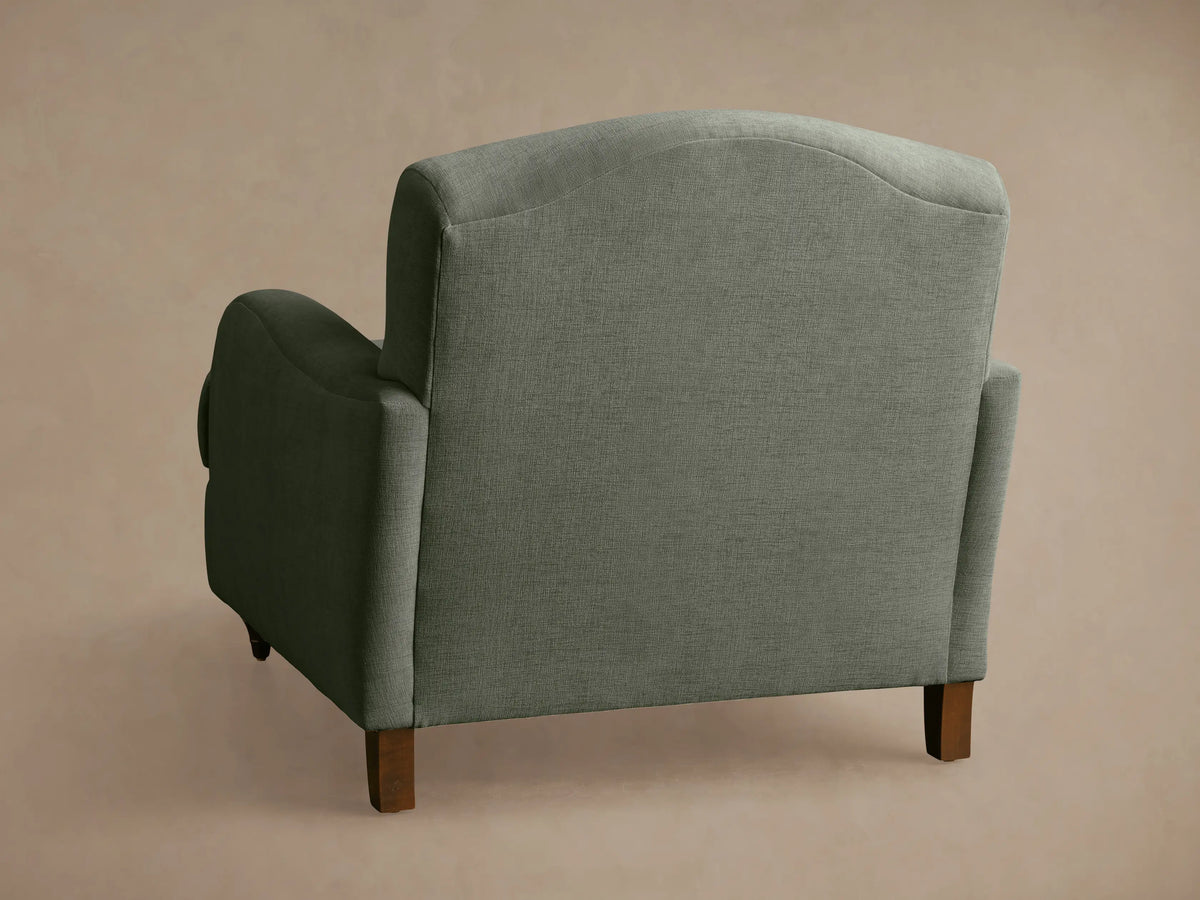 Close-up of Hanover Chair in deep olive green woven fabric. Curved armrest with elegant fluted details, plush back and seat cushions.