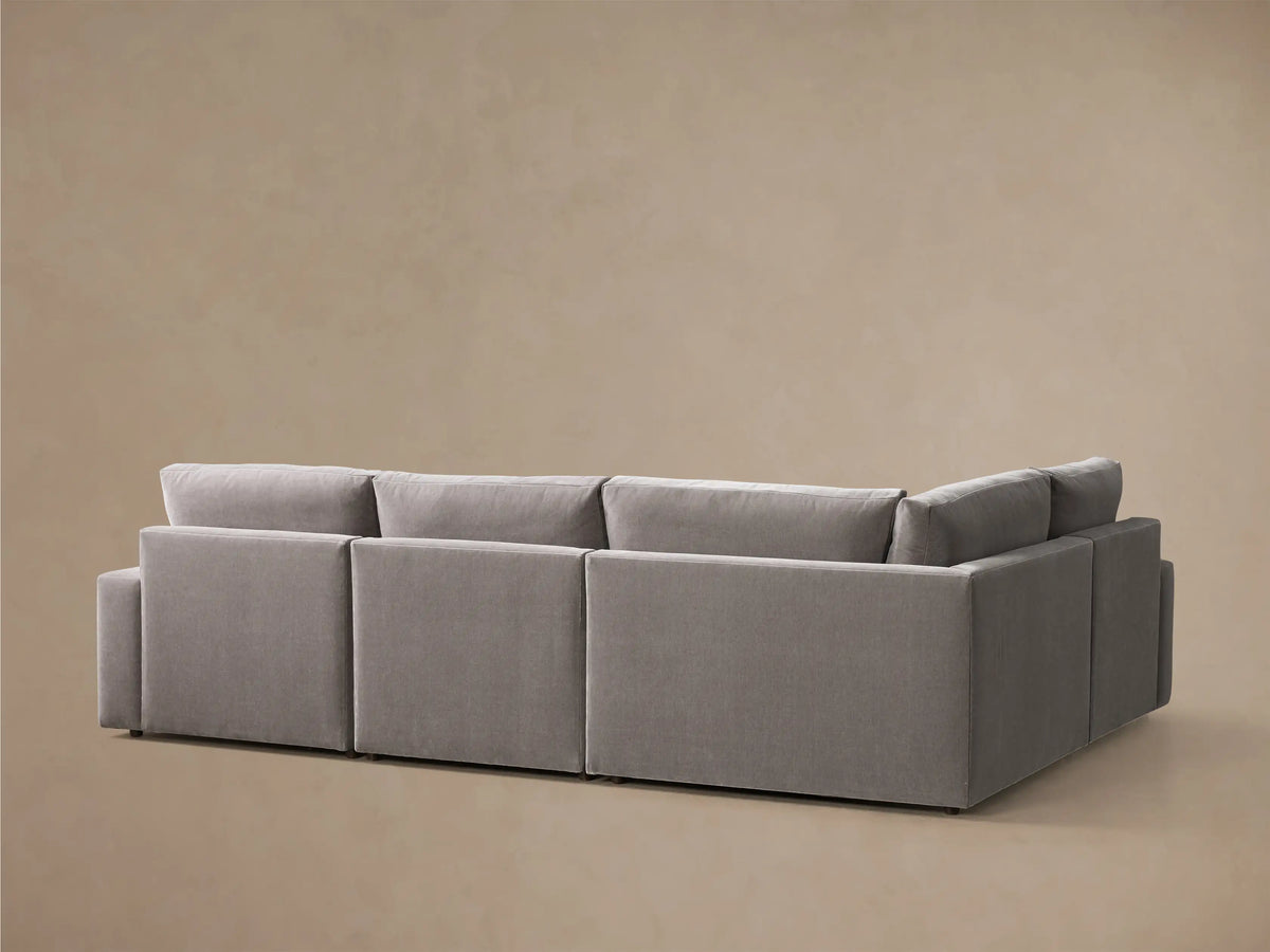 Close-up of a grey upholstered Kipton Wide Arm Four-Piece Motion Sectional with its footrest extended.