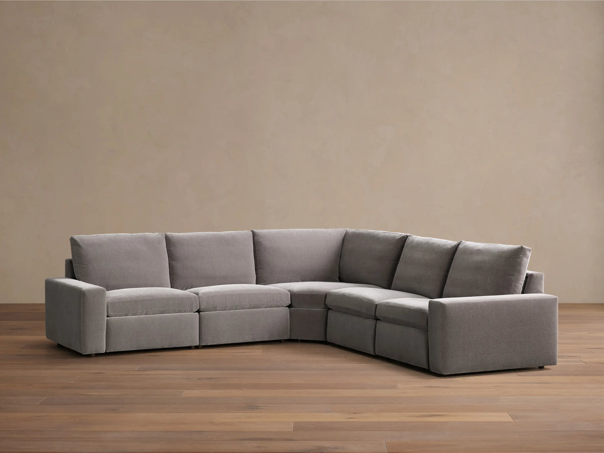 Front view of a grey Kipton Wide Arm Five-Piece Motion Corner Sectional, forming an L-shape with wide armrests.