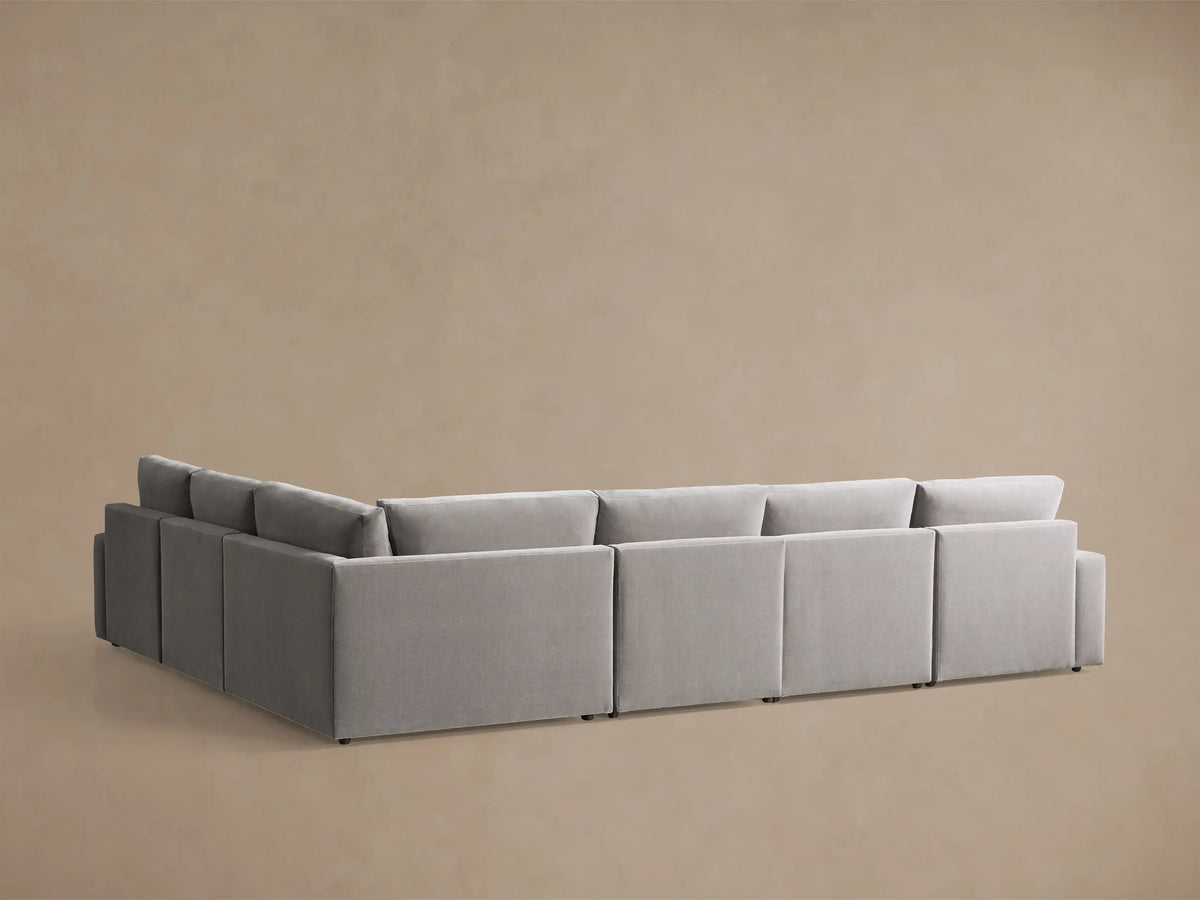 Close-up of the light gray Kipton Wide Arm Six Piece Motion Sectional with its wide arm and extended motion footrest.