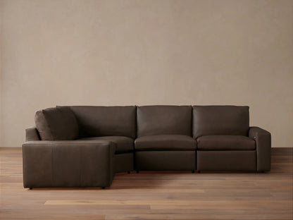 Dark brown leather Kipton Wide Arm Four-Piece Motion Sectional, L-shaped, on wood floor against light wall.