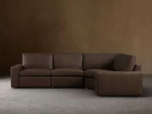 Dark brown leather Kipton Wide Arm Four-Piece Motion Sectional, L-shaped, on wood floor against light wall.