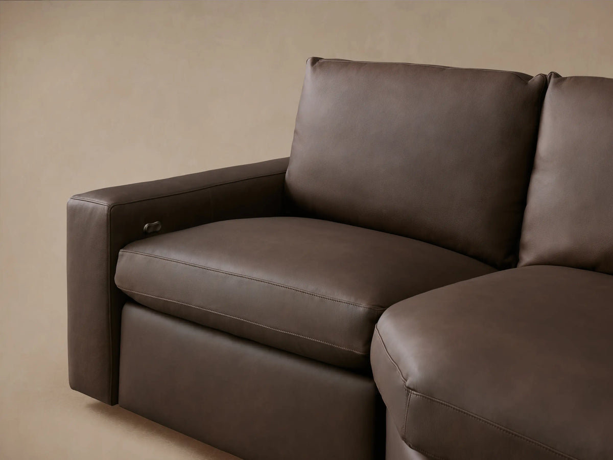 Close-up of Kipton Wide Arm Leather Motion Sectional, dark brown leather, detailed stitching, and chrome recline control.